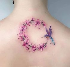 the back of a woman's neck with pink flowers and a hummingbird on it