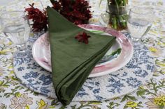 the napkin is folded on top of the plate with flowers in vases behind it