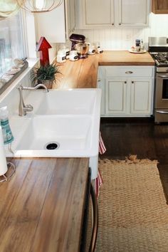 a kitchen with white cabinets and wooden counter tops, along with a sink in the center