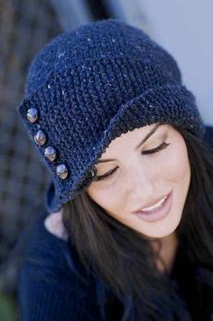 a woman wearing a blue knitted hat with silver buttons on it's brim