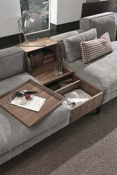 a living room with grey couches and a coffee table in the middle that is open