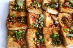 tofu with sesame seeds and scallions on a white plate