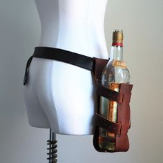 a white mannequin wearing a leather belt holding an empty bottle in it's back pocket