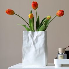 a white vase with orange and yellow tulips in it