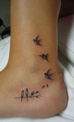 a small tattoo on the foot of a woman with birds flying around it and one bird sitting on top of another