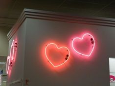 two neon signs on the side of a building with one heart and the other word love