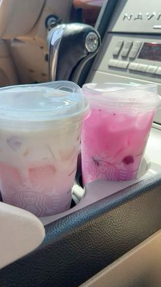 two plastic cups filled with liquid sitting on top of a car console