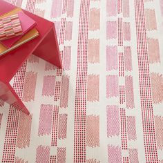 a red and white table sitting on top of a floor next to a pink chair