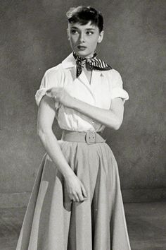 an old black and white photo of a woman wearing a skirt with a bow tie