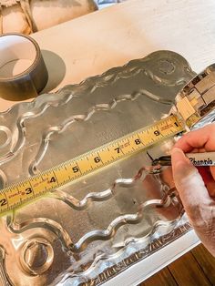 a man is measuring the width of a piece of tin foil with a tape measure