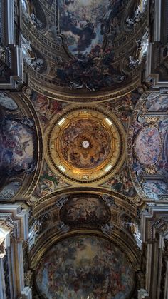 an ornate ceiling in a church with paintings on the walls and ceiling lights above it