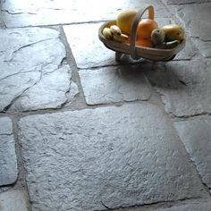 a basket filled with fruit sitting on top of a stone floor