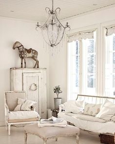 a living room filled with furniture and a horse statue on top of a cabinet next to a window