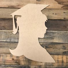 the silhouette of a person with a graduation cap on their head is mounted to a wooden wall