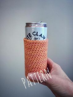 a hand holding up a can holder made out of knitted material