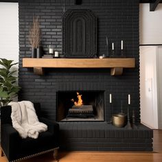 a living room with a black brick fireplace and white fur blanket on the chair next to it