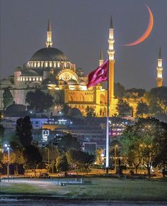 a large building with two towers and a crescent in the sky above it at night