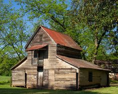 an old wooden building with a rusted tin roof in the middle of a field