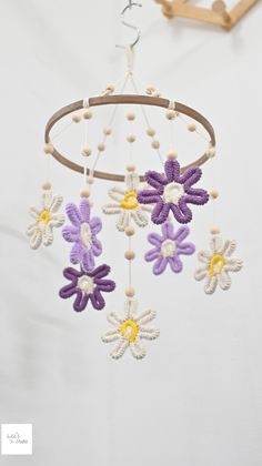 a crocheted flower mobile hanging from a wooden hanger on a white wall