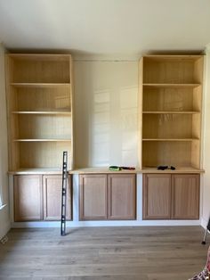 an empty room with wooden cabinets and ladder