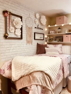 a bedroom with white brick walls and pink flowers on the bedspread, pillows and blankets