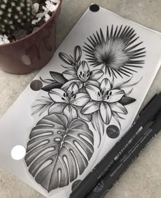 a black and white drawing of flowers next to a potted plant on a table