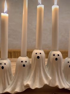 five white candles with black polka dots and ghost heads on them, lined up in a row