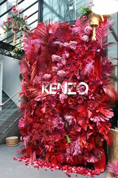 the entrance to kenzo's store is decorated with red flowers and greenery