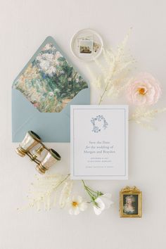 the wedding stationery is laid out on top of an envelope and some other items