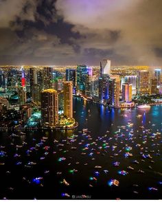 an aerial view of a city at night with boats in the water and colorful lights