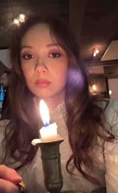 a woman holding a candle in front of her face