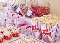 a table topped with lots of cupcakes and popcorn