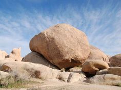 a large rock sitting on top of a pile of rocks under a blue cloudy sky