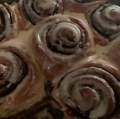 cinnamon rolls with icing sitting on top of a pan