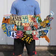 a man standing in front of a white building with lots of license plates on it