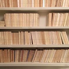 a bookshelf filled with lots of white books next to a wall mounted clock