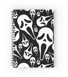 a spiral notebook with black and white ghost faces on it, surrounded by other spooky shapes