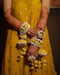 a woman in yellow dress holding flowers and bracelets