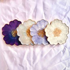 three different colored flowers sitting on top of a white sheet with gold flecks