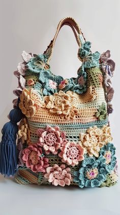 a crocheted bag with flowers and tassels on the front, sitting on a white surface