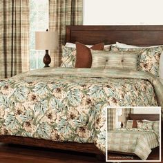 a bed with floral comforter and pillows on top of it in a bedroom next to a window