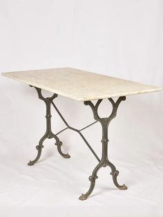 an old table with wrought iron legs and a white marble top on a white background