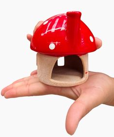 a hand holding a small red mushroom house