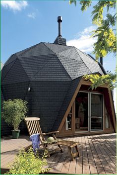 a wooden deck with a chair on it and a large black building in the background