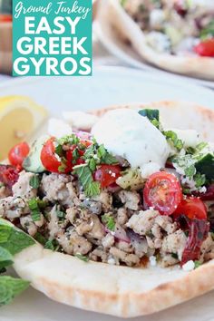 a plate with pita bread topped with meat and veggies, next to a lemon wedge