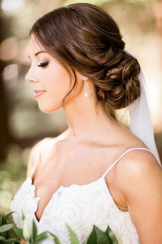 a woman in a wedding dress holding a bouquet and looking off into the distance with her eyes closed