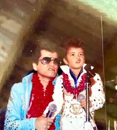 a man standing next to a young boy in front of a microphone