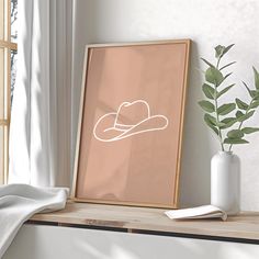 a frame with a cowboy hat on it next to a potted plant