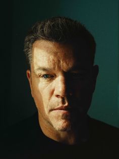 a close up of a person wearing a black shirt and looking at the camera with a serious look on his face