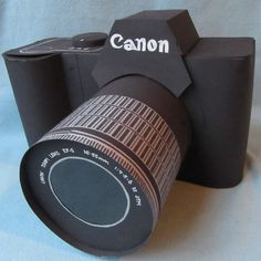 an image of a camera made out of paper on a blue cloth background with the word canon printed on it